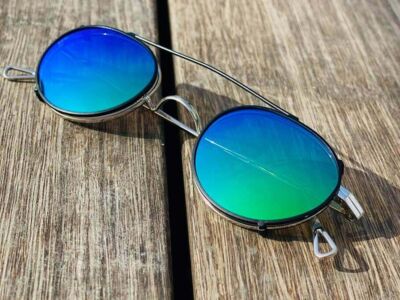 Brille mit Sonnenclip in  Grün-Blau auf Holztisch